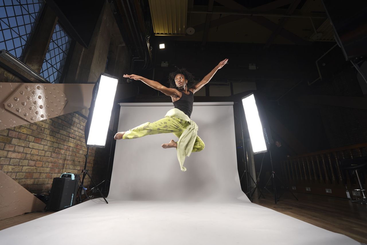 Sony A7 V sample images &ndash; dancer leaping into the air in a studio, with background roll and lights included in the frame