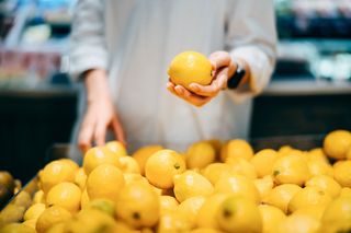 Woman holding lemons, as citrus fruits are a great part of a healthy liver detox