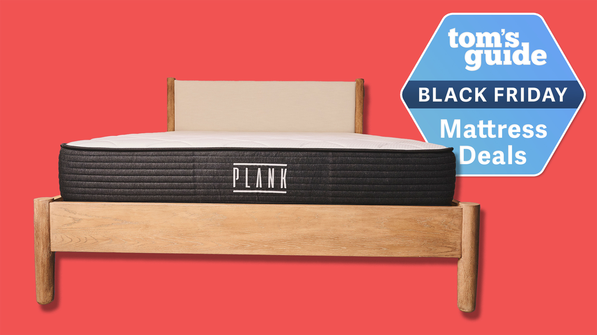 The Plank Firm Mattress on a wooden bed frame against a red background. A Tom&#039;s Guide Black Friday mattress deals badge in the top right corner