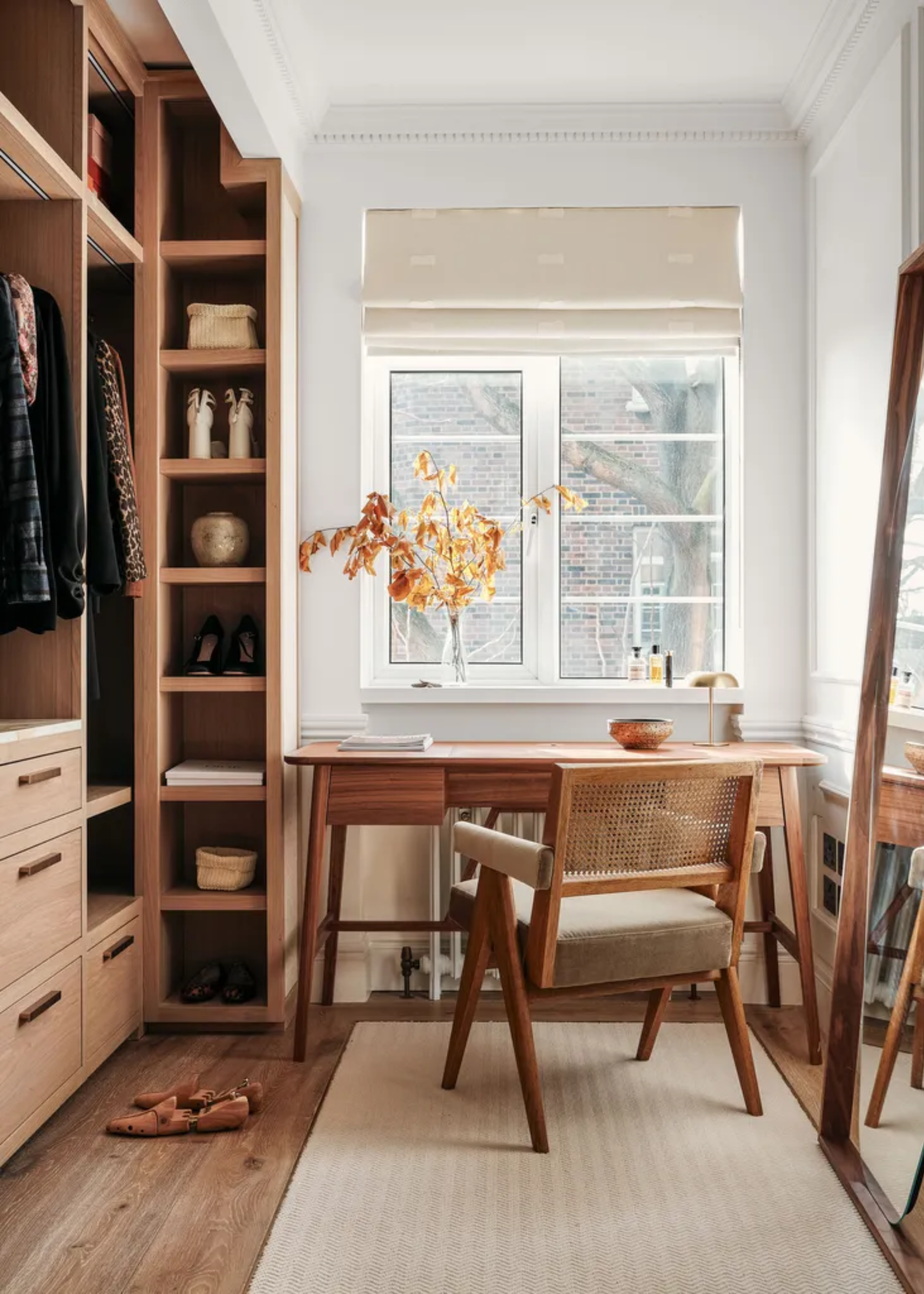 A minimalist wardrobe with open shelving and drawers opposite a full-size floor-length mirror