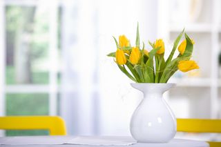 A vase of yellow tulips sits in a kitchen