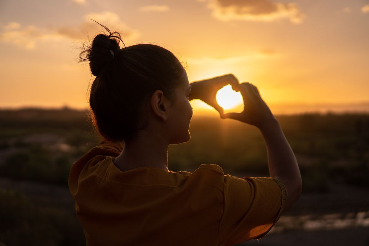 Woman making heart sign around setting son