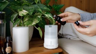 A woman adding essential oils to a diffuser