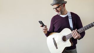 Man with a guitar using his phone