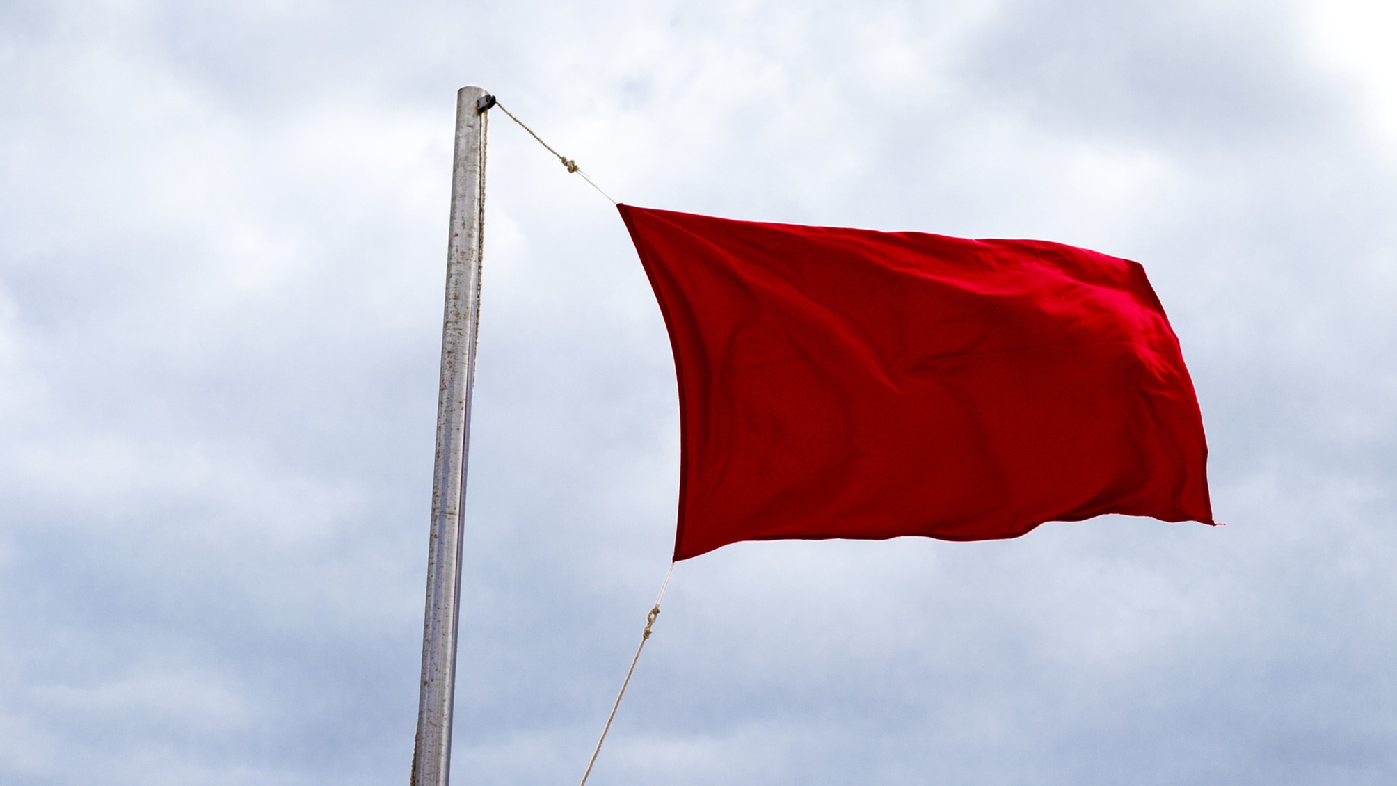 A red flag against the backdrop of a cloudy sky.