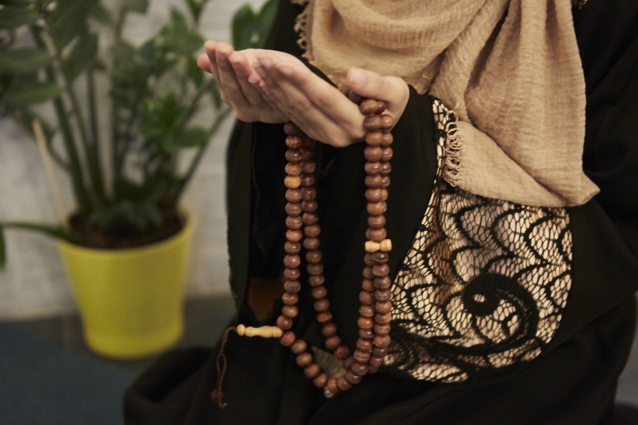 A Muslim woman holding a wooden string of prayer beads.
