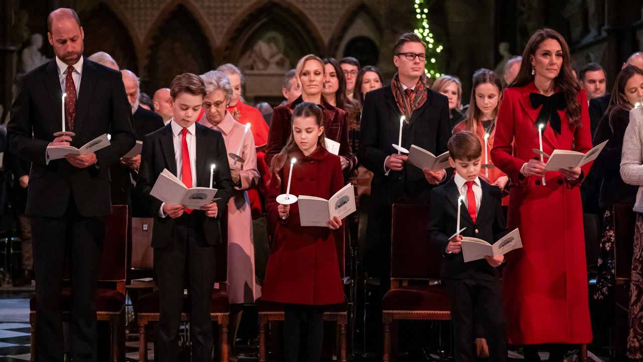 Prince William, Prince George, Princess Charlotte, Prince Louis and Kate Middleton wearing red and blue dress clothes in church holding candles and singing