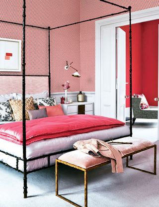 Pink bedroom with patterned wallpaper and black four poster bed