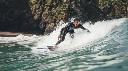 Surfers riding waves wearing wetsuits