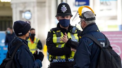 A member of the British Transport Police speaks with travellers at Waterloo Station