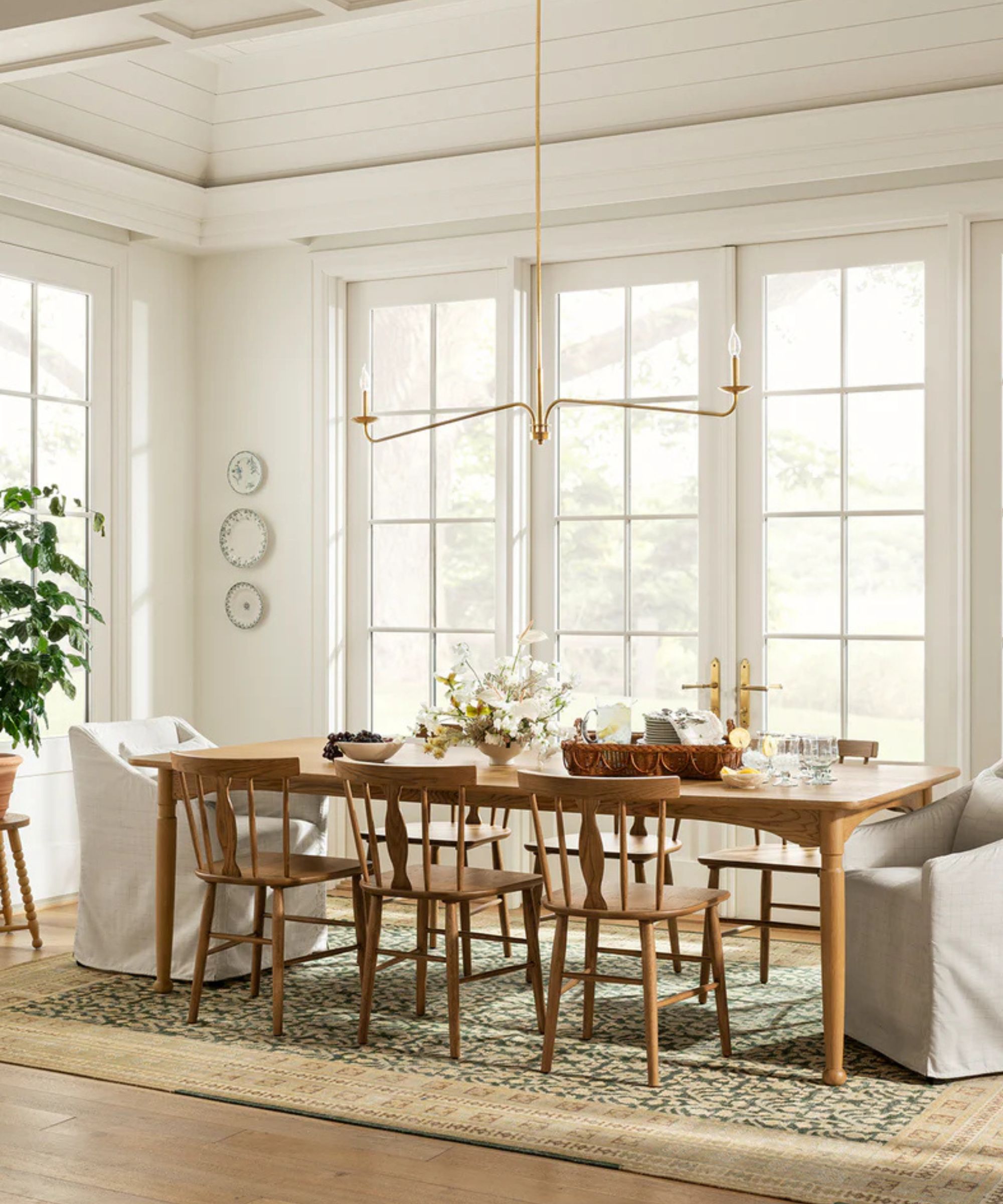 Dining room with white wood panelling, wood long dining table, wood dining chairs and low pendant light