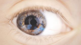 close up of a child's brown eye; you can see the interior of an eye doctor's office lightly reflected in the eye