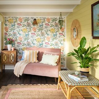 A small living room with a panelled butter yellow wall and a pink chair bed