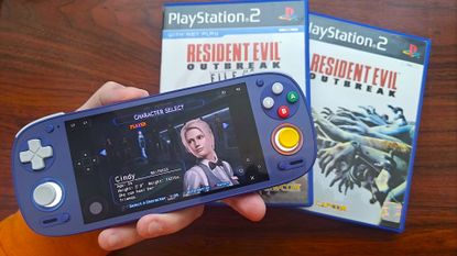 Hand holding Retroid Pocket 5 with Resident Evil Outbreak web version running and Cindy selected on character screen with original PS2 copies of File #1 and File #2 in backdrop.