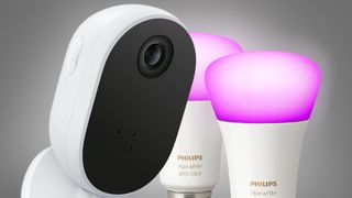 The WiZ Indoor security camera next to two Philips Hue lightbulbs on a grey background