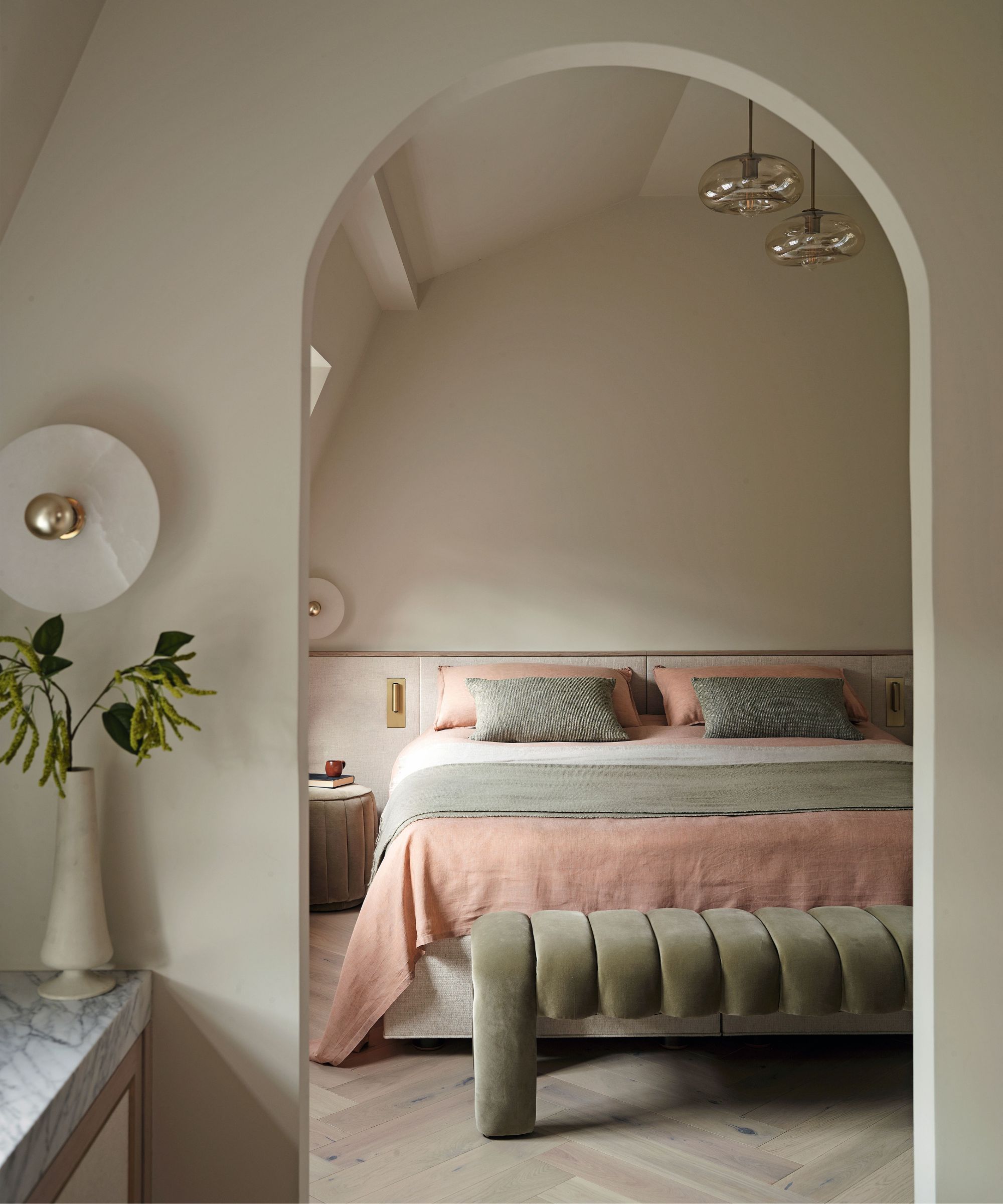 a white pink and green bedroom with an arched entry door