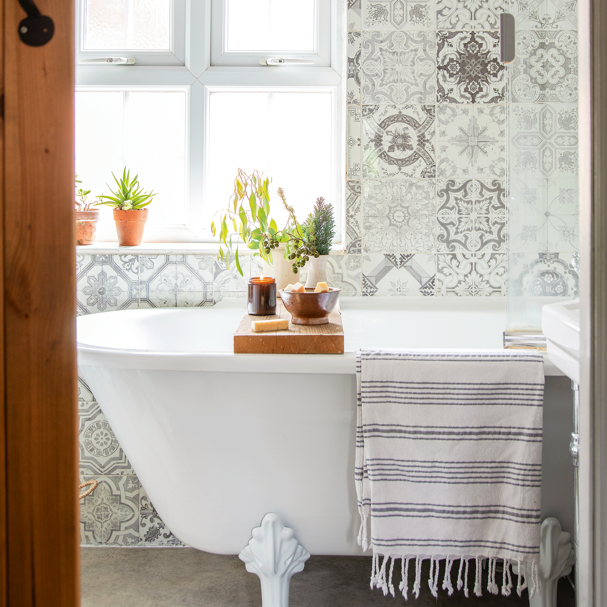 a bathroom with a large traditional bath tub and patterned tiles