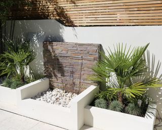 slate clad garden wall used as a backdrop to a small water feature