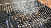 A lit charcoal grill with smoke rising through the iron grills.