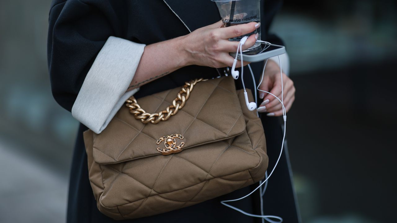 Woman with subtle shimmery nails holding earphones and Chanel handbag - best shimmery nail polishes