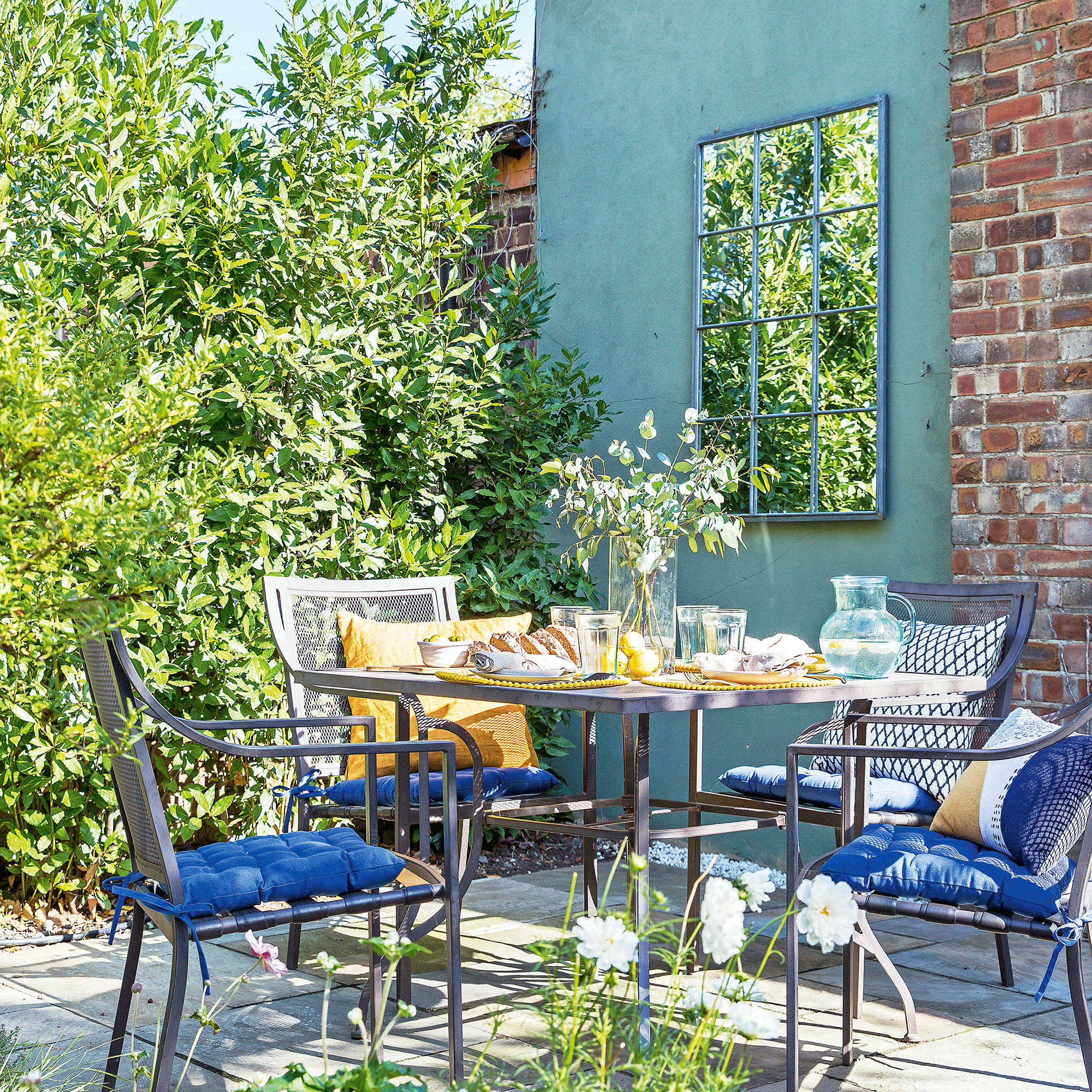 Blue wall in garden with metal furniture