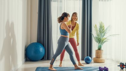 Two women in activewear surrounded by exercise equipment