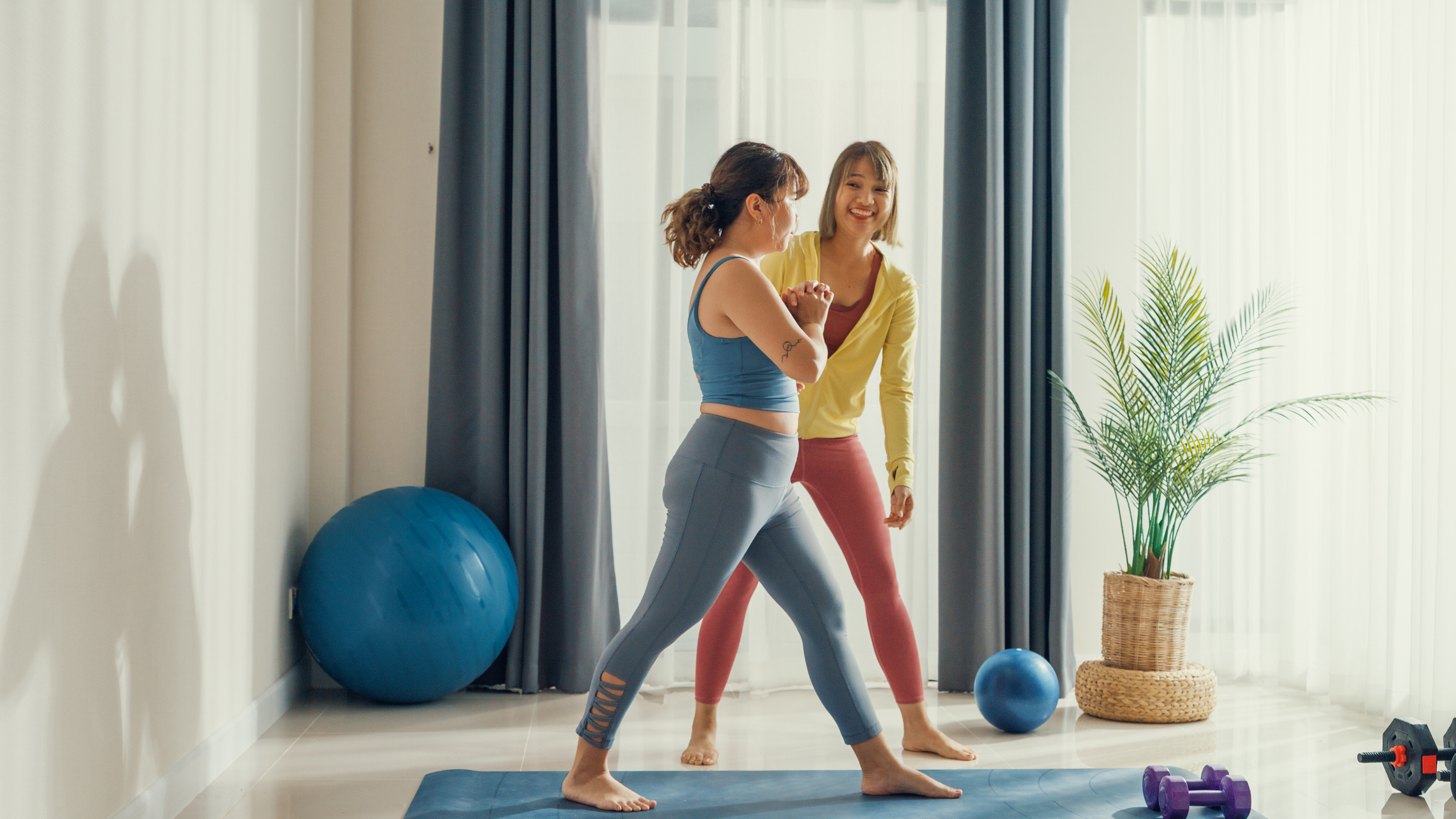 Two women in activewear surrounded by exercise equipment