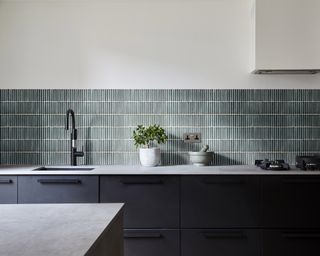 Small gray kitchen wall tile ideas as a backsplash in a white kitchen with dark gray cabinetry.