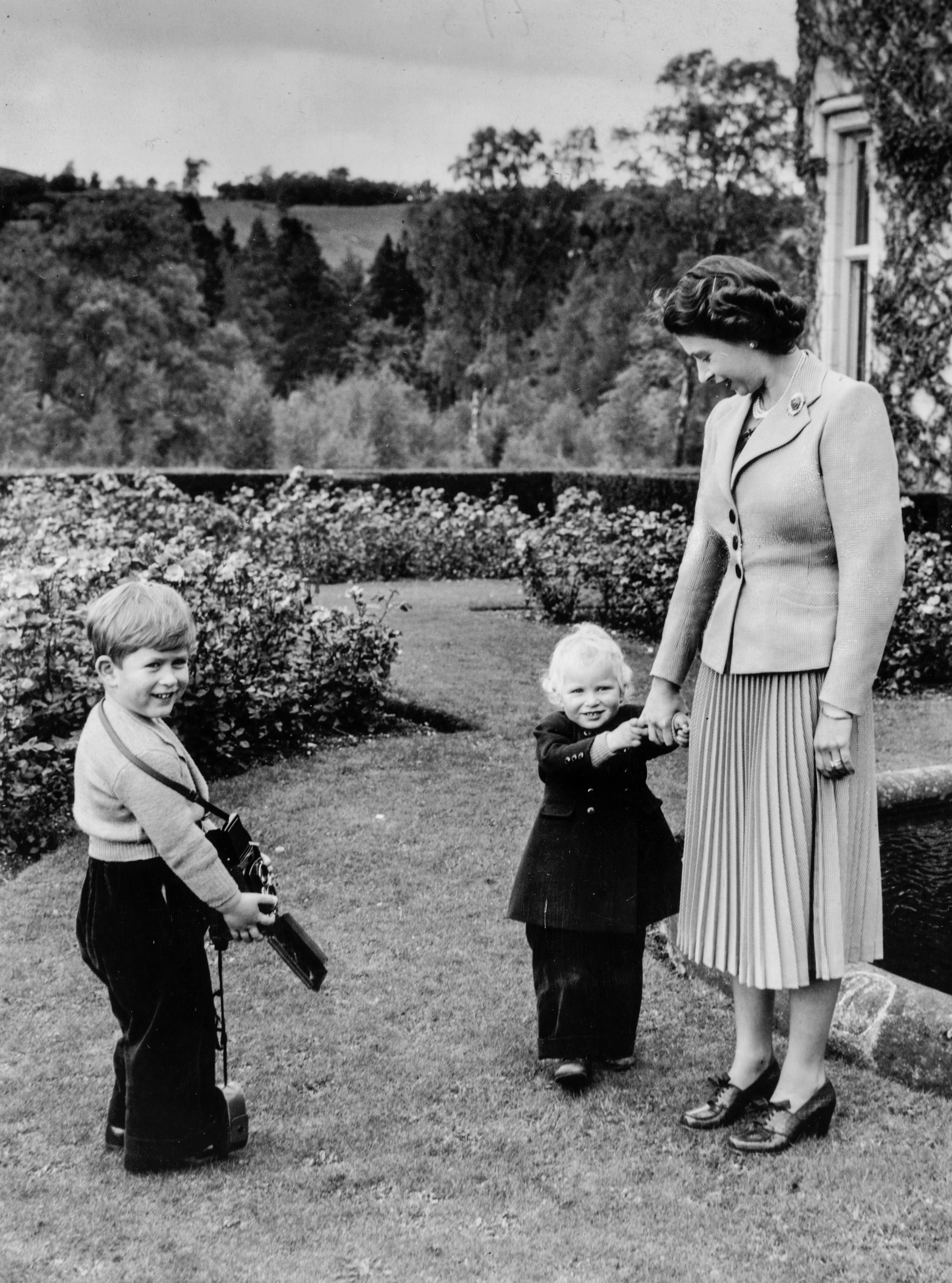 28th September 1952: Queen Elizabeth II plays with her children, Charles and Anne in the grounds of Balmoral Castle, Scotland