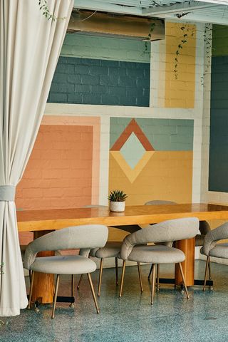 The pastel-shaded, mid-century modern "Palm Springs" outdoor patio of Avalon Hotel Beverly Hills features colorful brick murals and wooden and upholstered furniture.