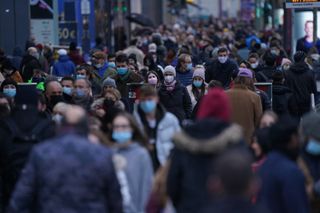 a crowded city street full of people wearing surgical masks of a variety of colors