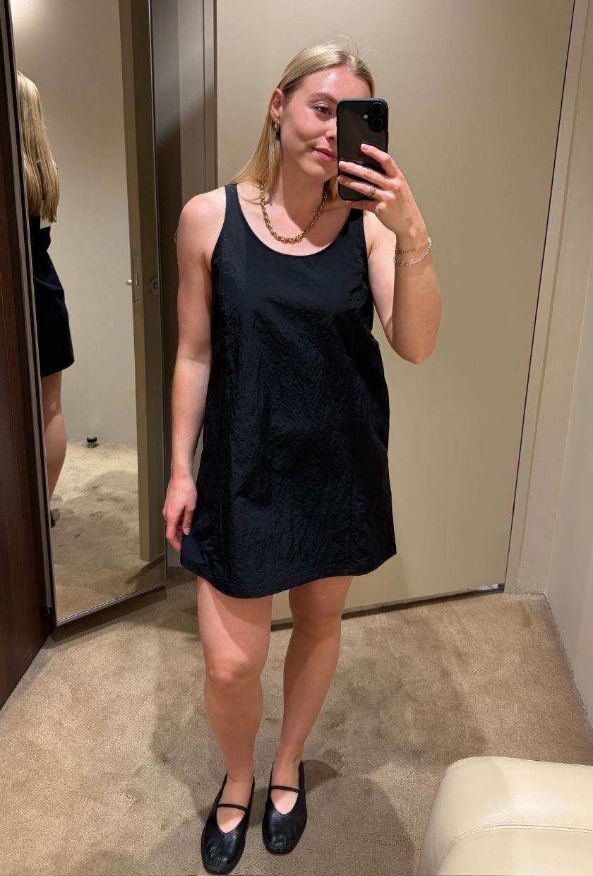 Woman wears black mini dress and ballet flats