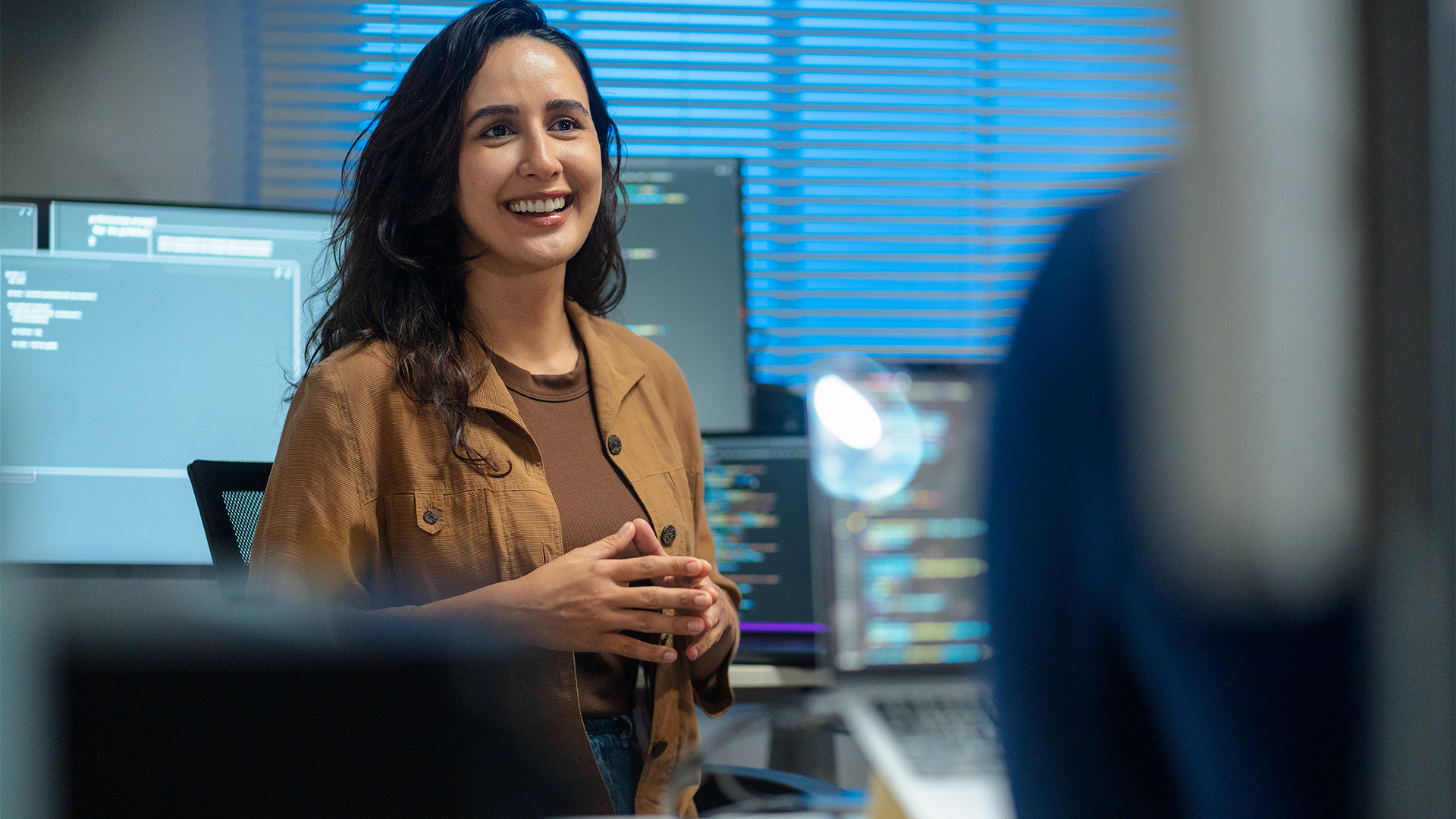 Male and female data streaming engineers pictured in an open plan office space discussing strategy with software applications open on computer screens in background.