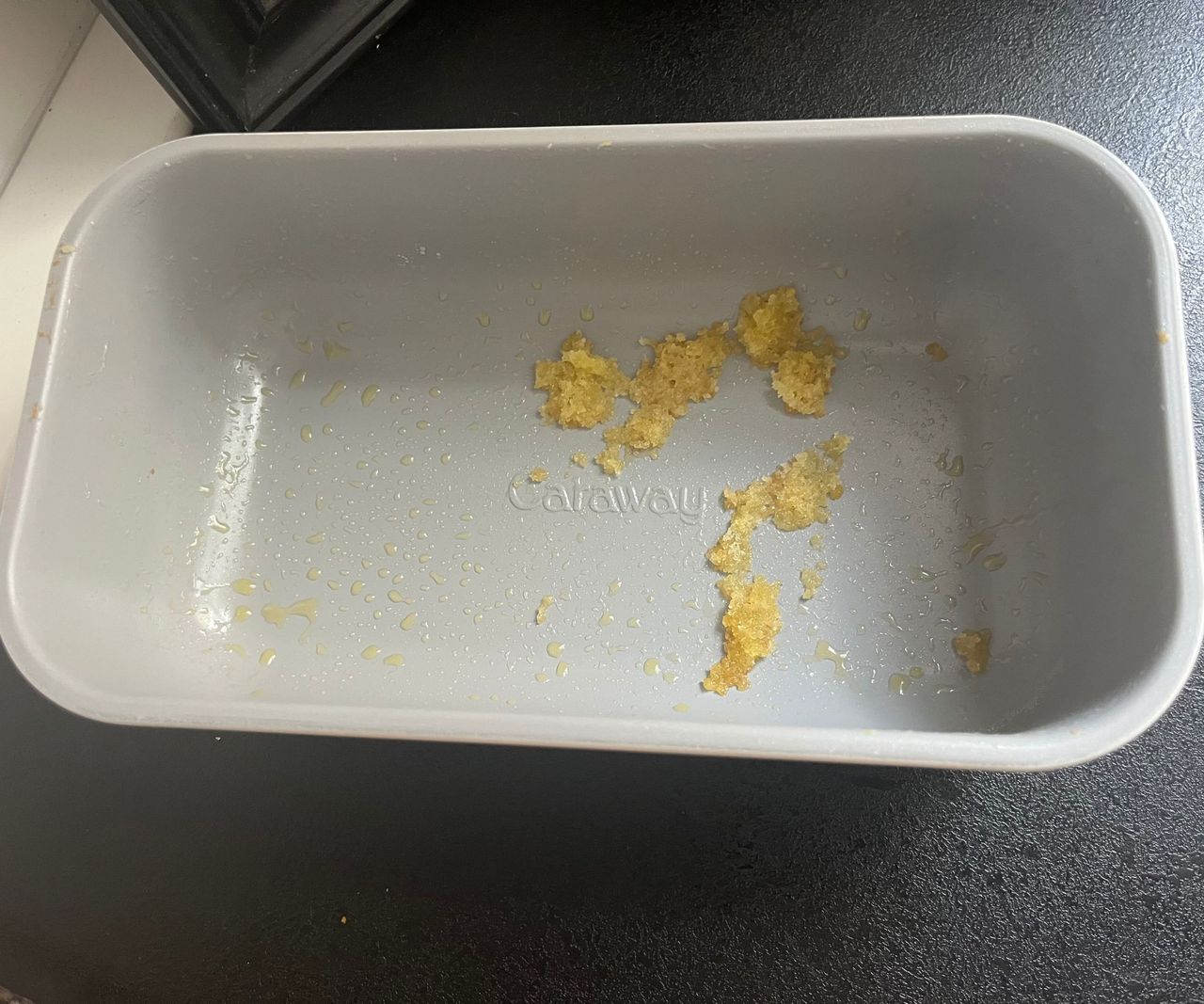 A grey loaf tin with cake stuck inside