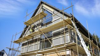Building company gone bust - house exterior with scaffolding and builder doing work