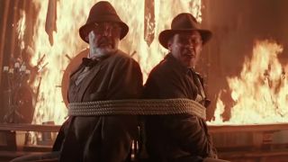 Sean Connery on the left, tied up to Harrison Ford with a fire burning behind them in Indiana Jones And The Last Crusade