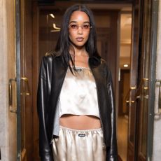 Laura Harrier wears a knee-length satin skirt.