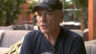 Bruce Dickinson in a black t-shirt and black baseball cap in 2025
