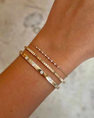 Woman wearing diamond bracelet stack with gold inlaid diamond cuff and fluted diamond bracelet from Ring Concierge.