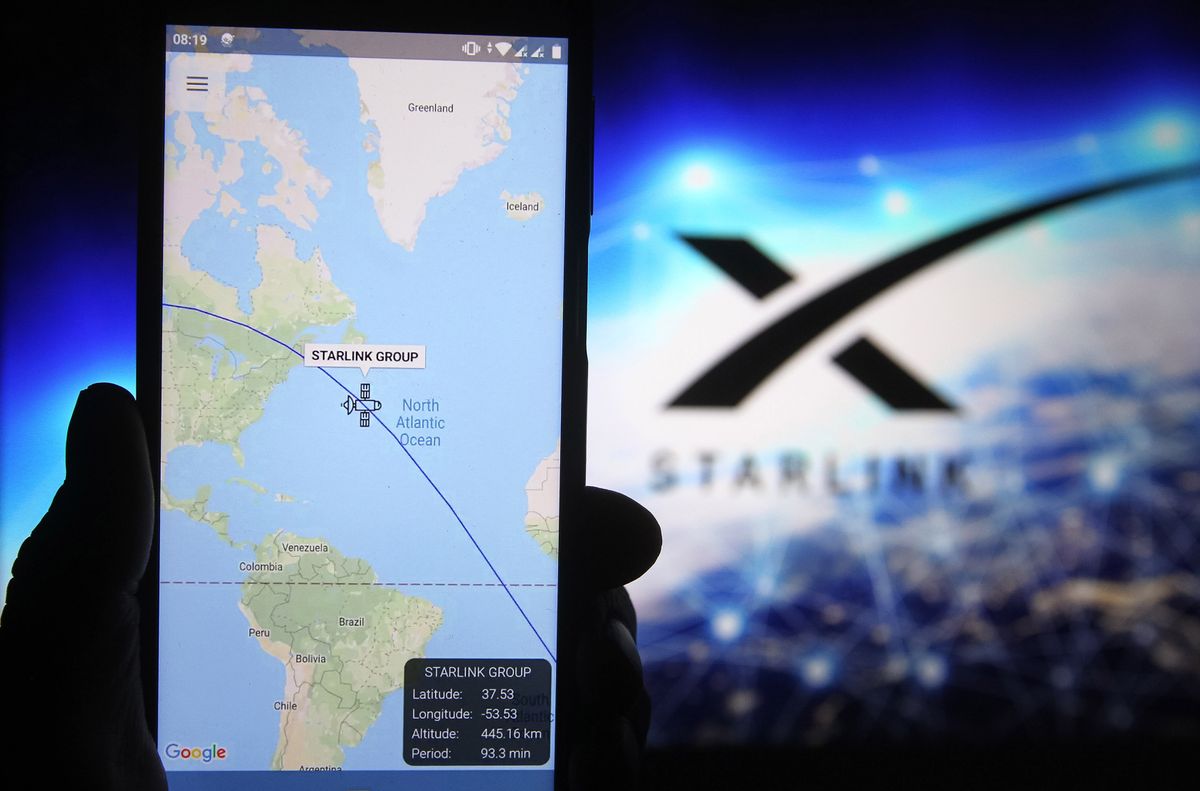 Starlink satellite tracker image in focus on phone with Starlink logo in background