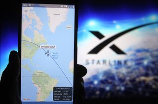 Starlink satellite tracker image in focus on phone with Starlink logo in background