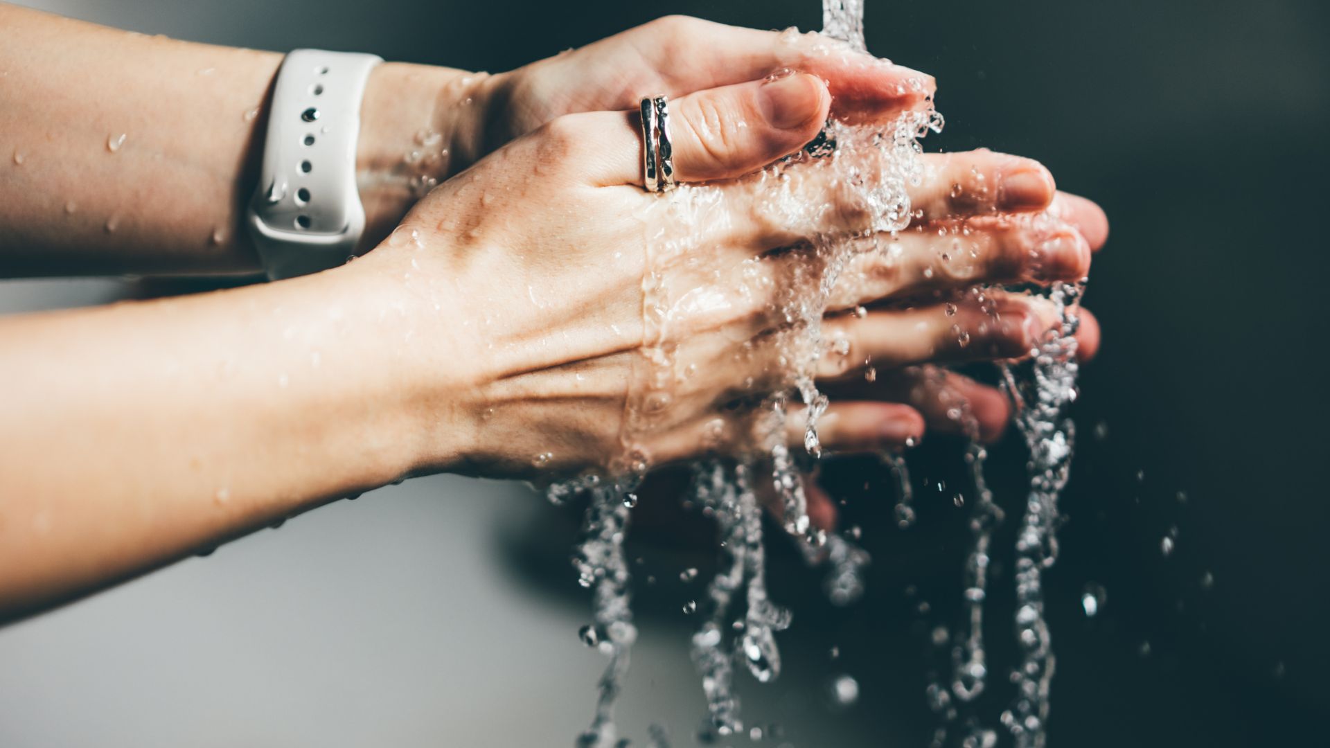 Woman washing hands over sink wearing watch
