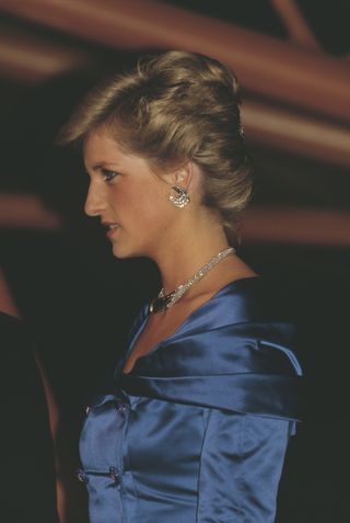 A side profile of Princess Diana wearing a blue satin gown and diamond necklace