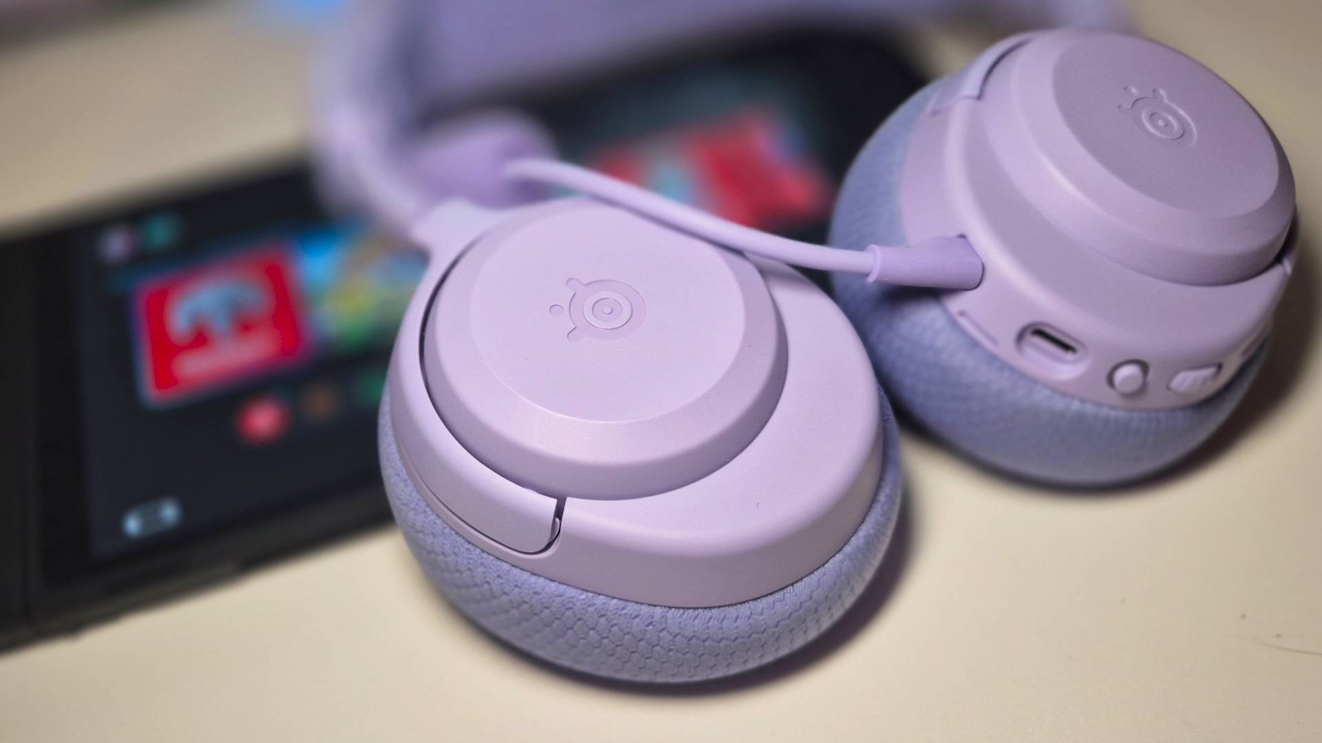 Photo of the Lavender Arctis Nova 3 Wireless headset resting on a Nintendo Switch 2.