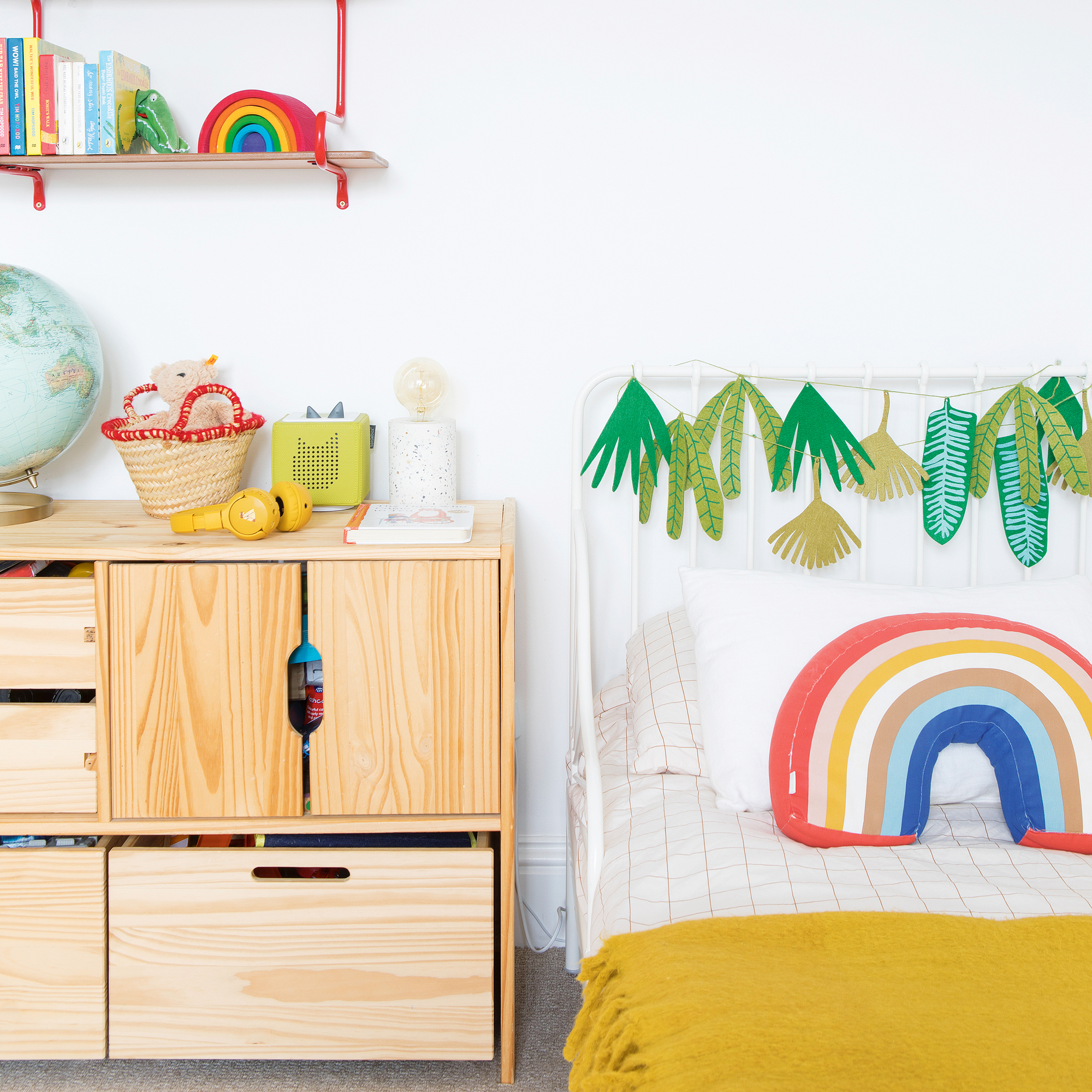 a colourful kids room with rainbow patterns, wooden storage furniture and red shelving