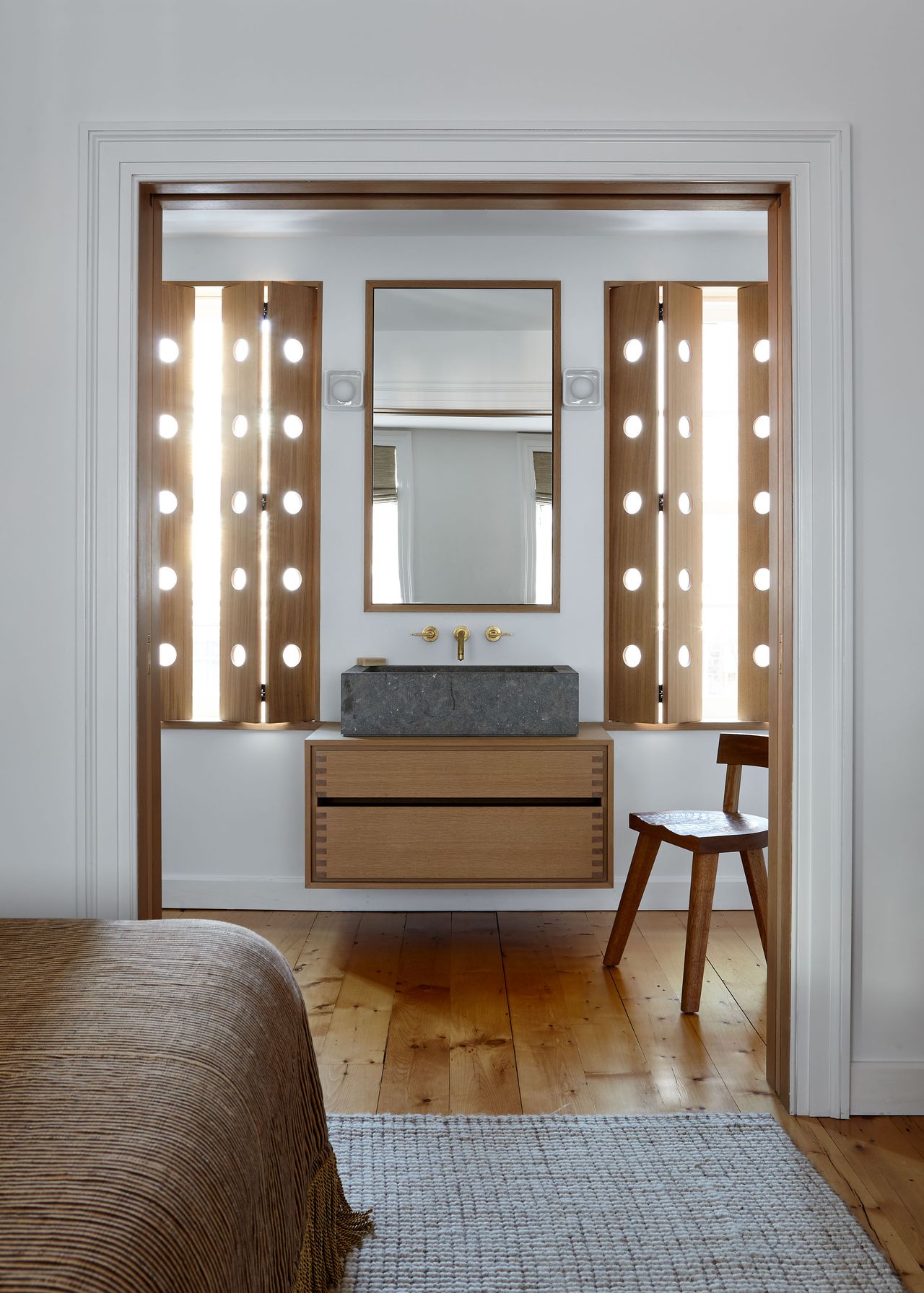 En suite bathroom with concrete sink, wooden floating vanity and light-filtering shutters