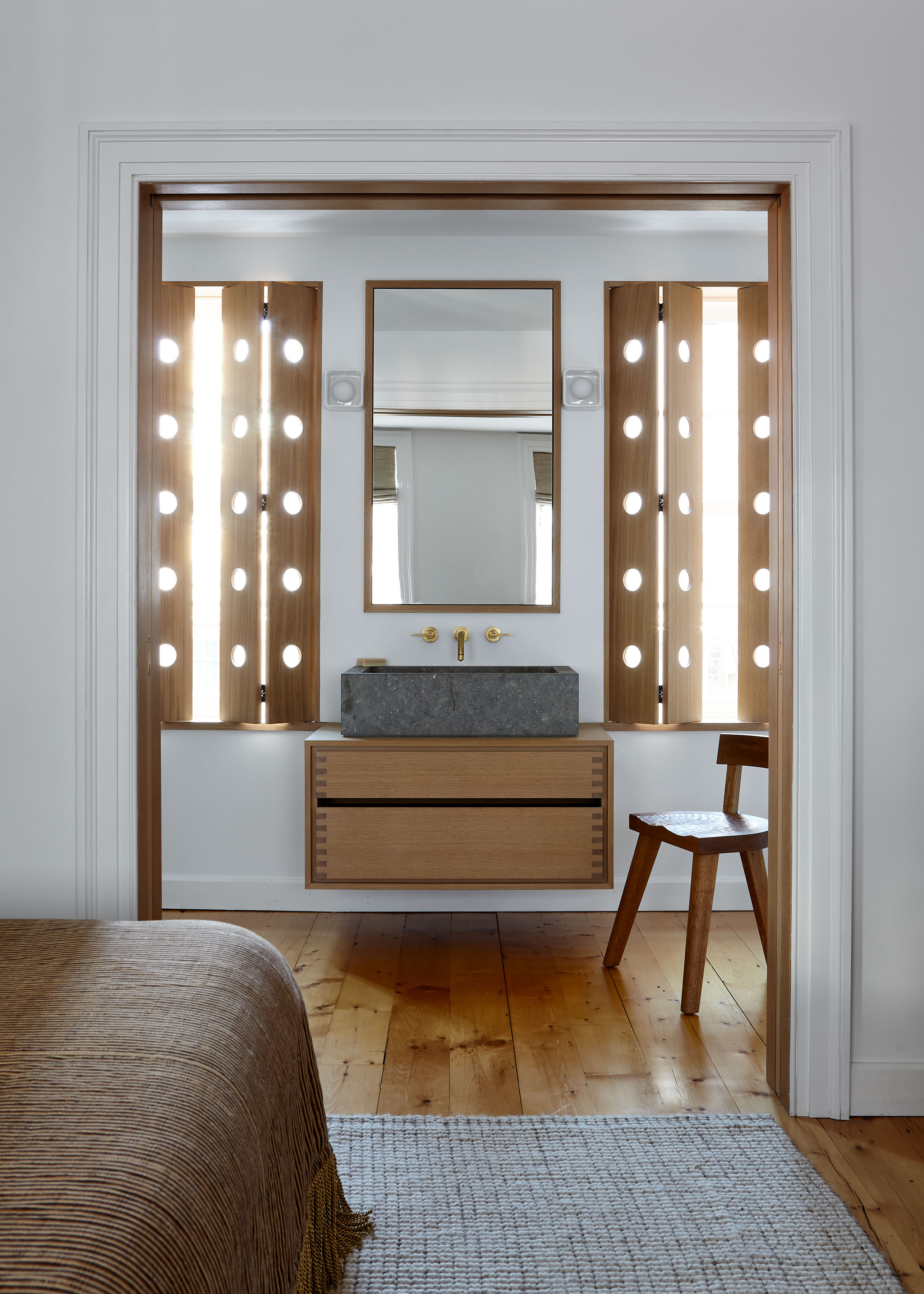 En suite bathroom with concrete sink, wooden floating vanity and light-filtering shutters