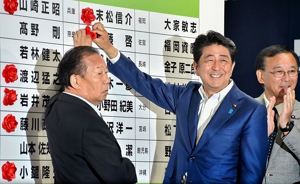 Japanese Prime Minister Shinzo Abe places a rosette next to the name of a parliamentary winner on Sunday.