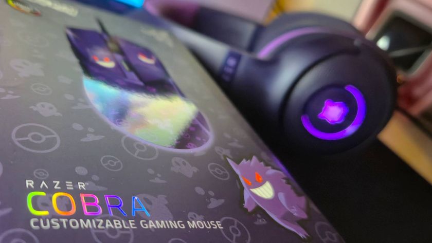 Close up of the front of the box of the Razer Cobra Gengar gaming mouse, with a lit-up matching purple gaming headset in the background.