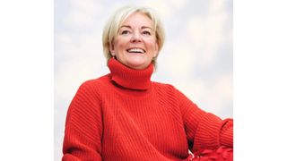 Image of Jo Malone smiling with short blonde hair and wearing a red knitted roll-neck jumper